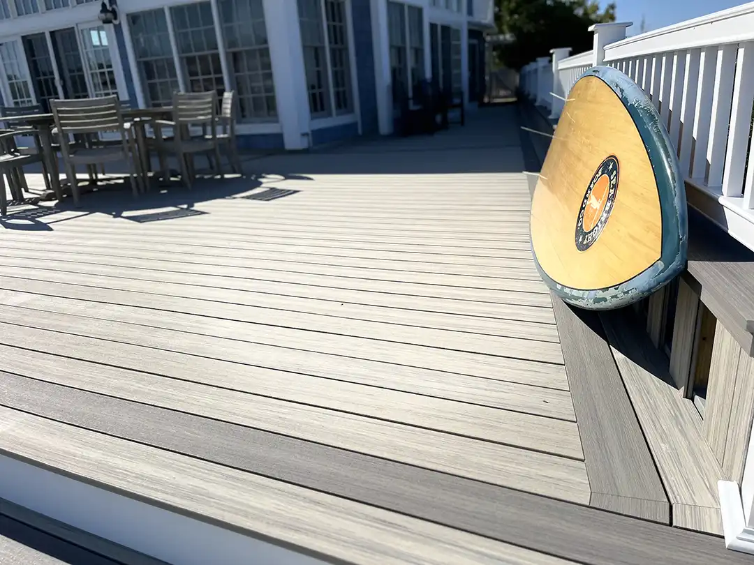 Photo of a wraparound composite deck with outdoor furniture and a surfboard.