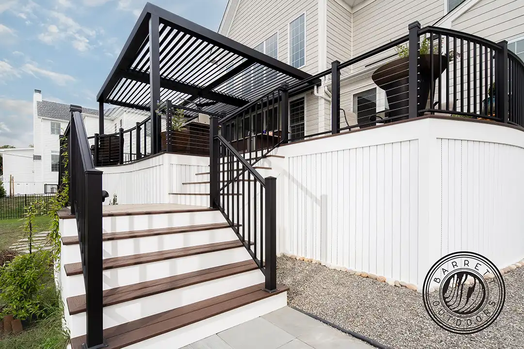 Custom deck with steps, black cable railing, and louvered pergola