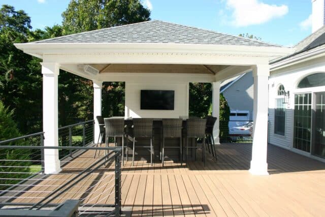 Photo of a composite deck with a covered entertainment and dining area with cable railing