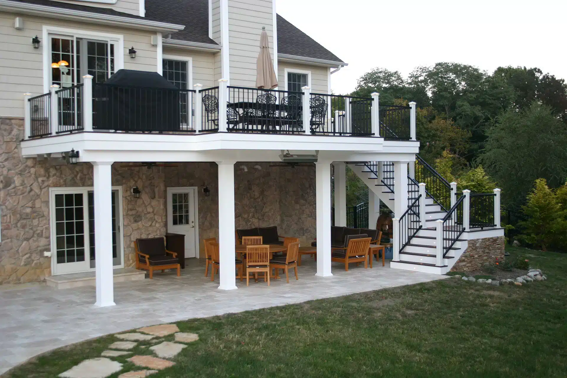 Photo of elevated deck with railing, steps, underdeck patio, and underdeck water diversion system